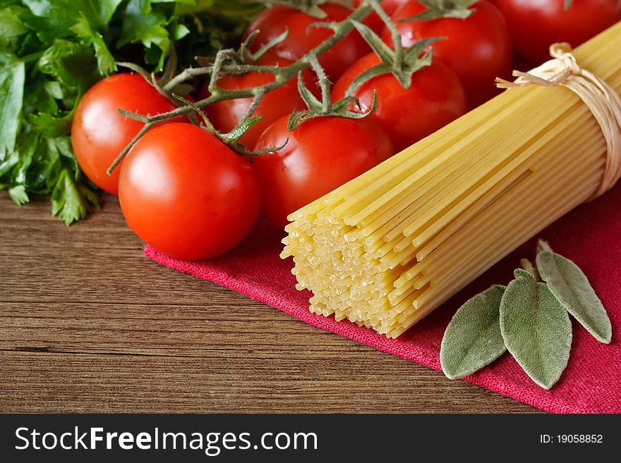 Spaghetti, cherry tomatoes and parsley on a wooden table. Spaghetti, cherry tomatoes and parsley on a wooden table.