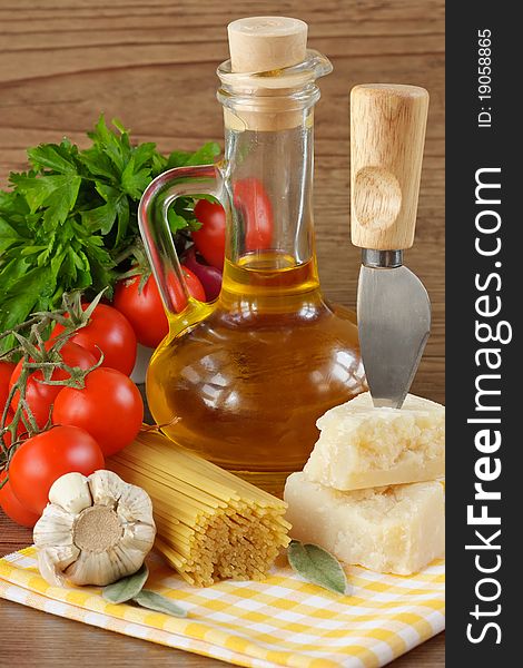 Italian pasta, parmesan, garlic, olive oil and tomatoes on a wooden table. Italian pasta, parmesan, garlic, olive oil and tomatoes on a wooden table.