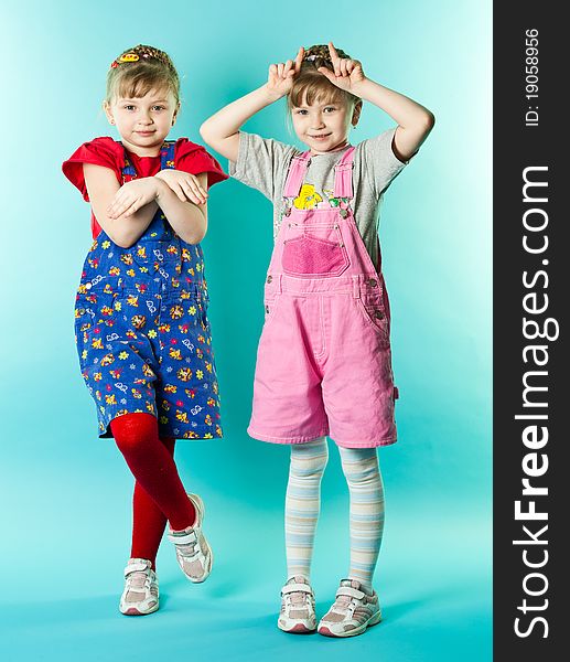 Two twin sisters posing over blue background