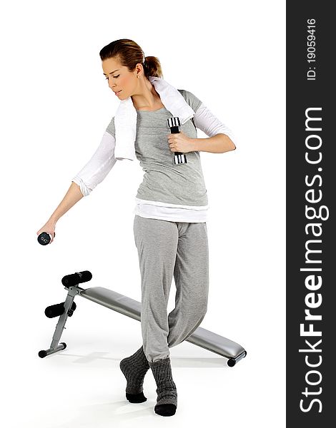 Girl exercising with weights with a bench in the background, on a white background. Girl exercising with weights with a bench in the background, on a white background