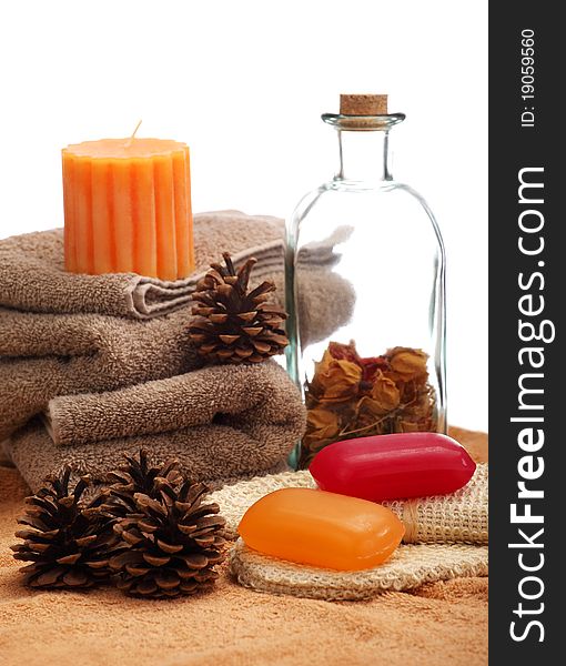 Soaps, bottle, candle, towels and pine cones placed on a towels, on a white background. Soaps, bottle, candle, towels and pine cones placed on a towels, on a white background