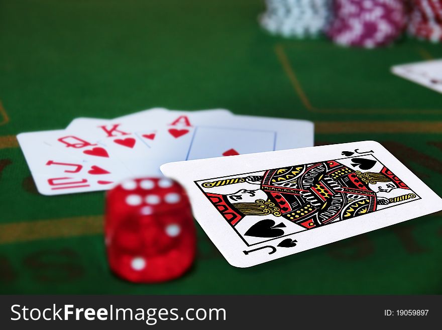 Green casino table with dice and a hand of a royal flush in a poker game and the jack of spades in the pack. Green casino table with dice and a hand of a royal flush in a poker game and the jack of spades in the pack