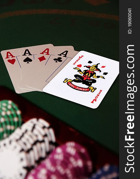 Green casino table with chips and four aces in a poker game and a joker in the pack. Green casino table with chips and four aces in a poker game and a joker in the pack