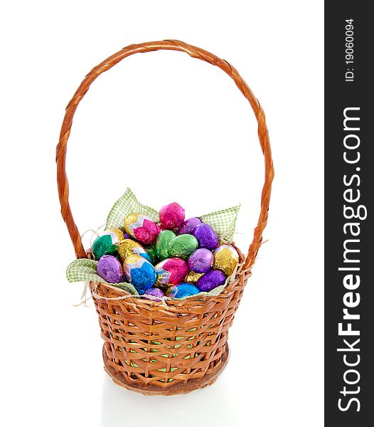 Colorful easter eggs in a wicker brown basket isolated on white background