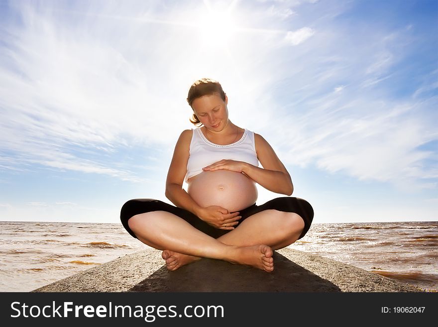 A pregnant woman on a rock.