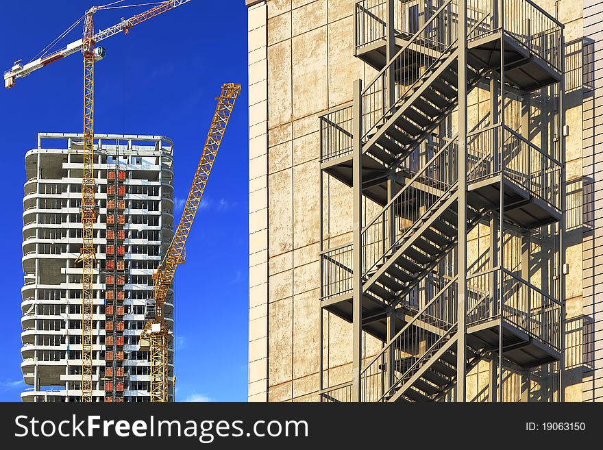 External ladder of a high-rise building on the building cranes background. External ladder of a high-rise building on the building cranes background