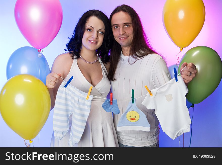 Happy pregnant couple holding baby clothe