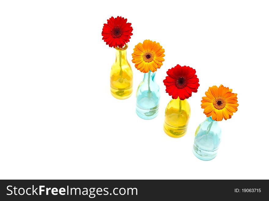 Photo consists of several gerbera flowers in vases of different colors. In this photo attracted the attention of the construction of objects and their colors