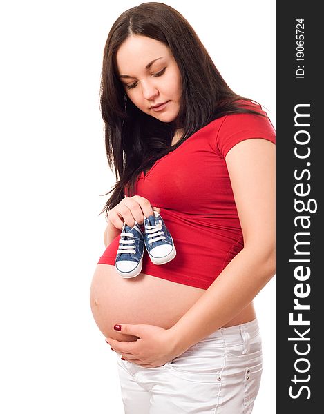 A pregnant woman holding baby shoes