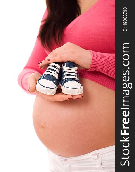 A pregnant woman holding baby shoes