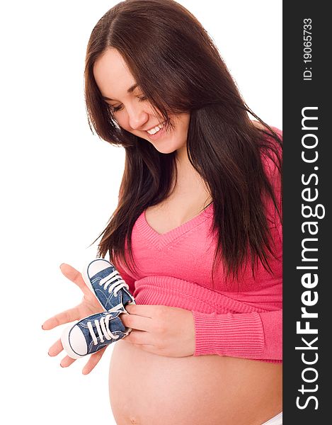 A pregnant woman holding baby shoes