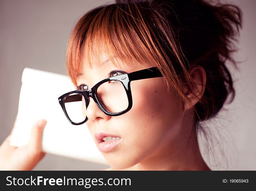 Asian girl holding a textbook. Wear a big black glasses. Asian girl holding a textbook. Wear a big black glasses.
