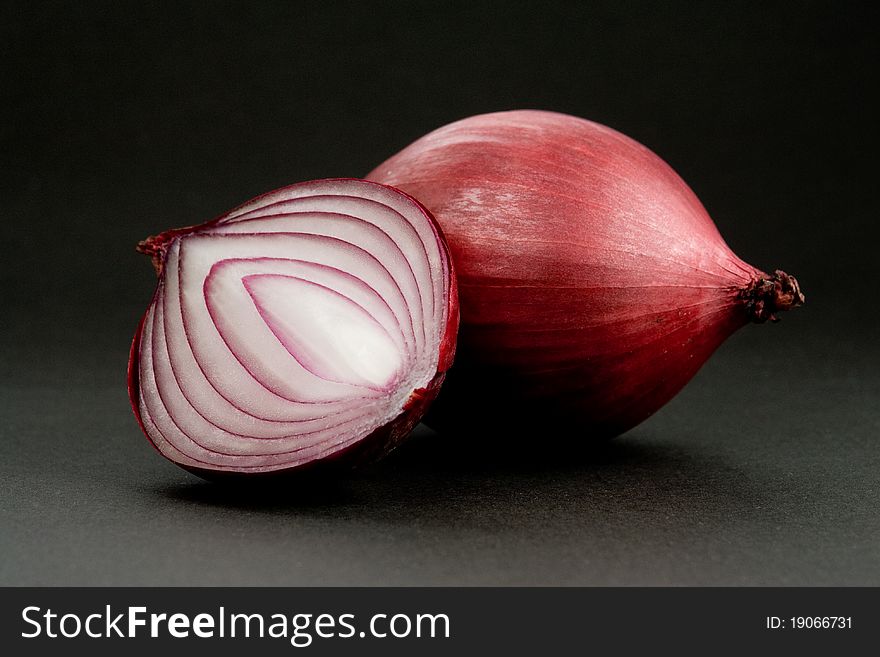 Red Onion and the cross section of it, over dark background