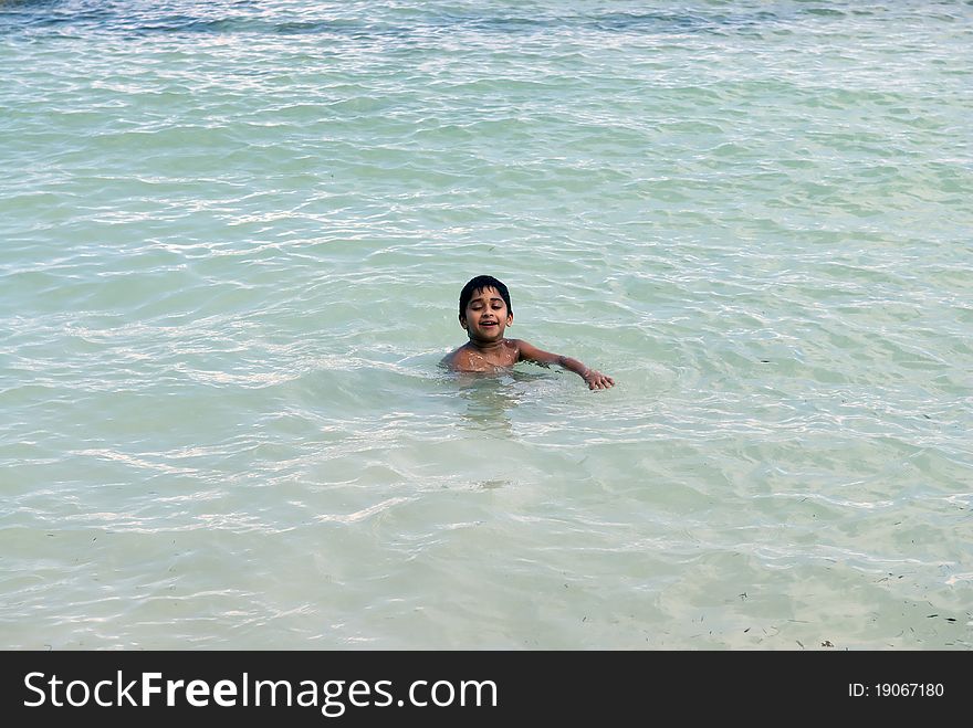 An handsome indian kid enjoying swimming at the ocean