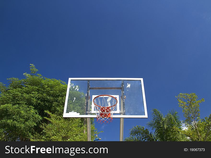 An old basketball hoop and net against a brilliant deep blue sky.