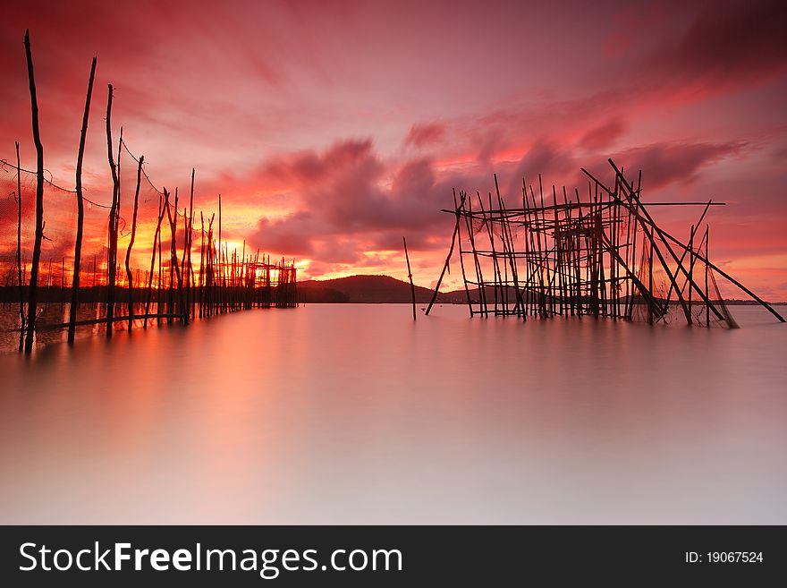 The fishermen uses the woods to make a fish trap. The fishermen uses the woods to make a fish trap