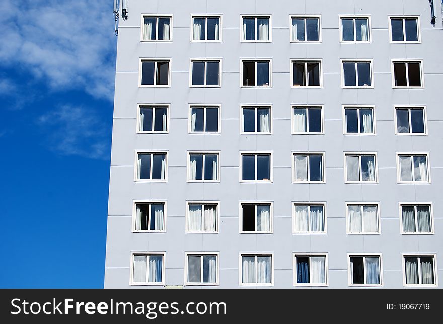 Grey building with big windows against blue sky