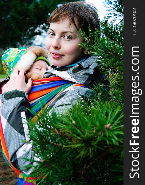 Young mother with her little boy sleeping in baby sling outdoor. Young mother with her little boy sleeping in baby sling outdoor