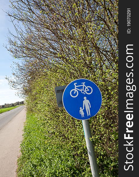 Hedgerow sign indicating a cycle and pedestrian footpath alongside a country lane. Hedgerow sign indicating a cycle and pedestrian footpath alongside a country lane