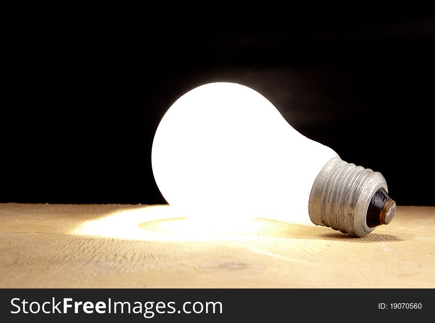 Bulb burning lying on a table. Concept. Bulb burning lying on a table. Concept