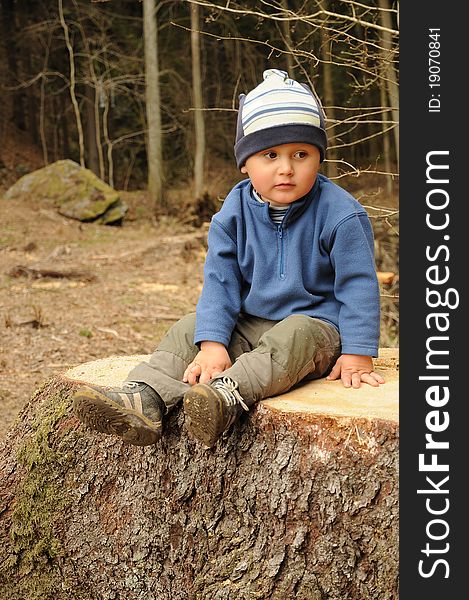 Little boy sitting on a tree stump and having rest. Little boy sitting on a tree stump and having rest