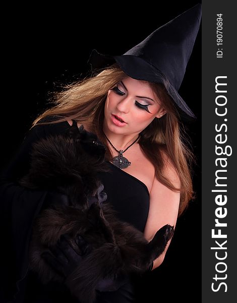 Beautiful girl dressed as a witch holding cat