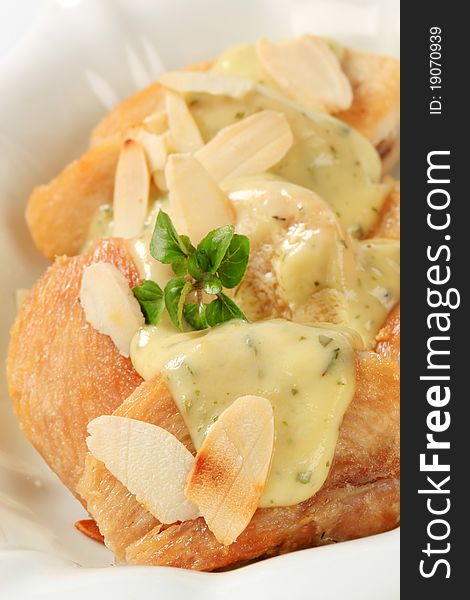 Slices of roasted chicken with herb sauce and almonds