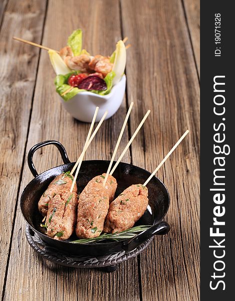 Raw minced meat kebabs on wooden skewers