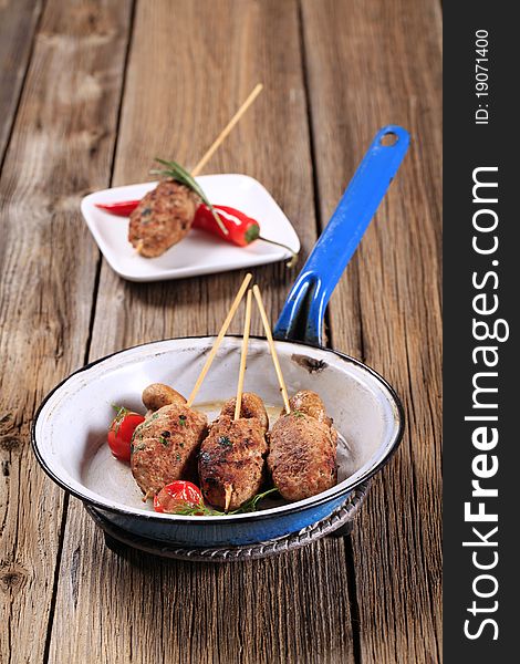 Minced meat kebabs on wooden skewers and mushrooms