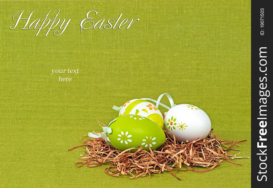 Easter composition: nest with three colorful eggs on a green flax background