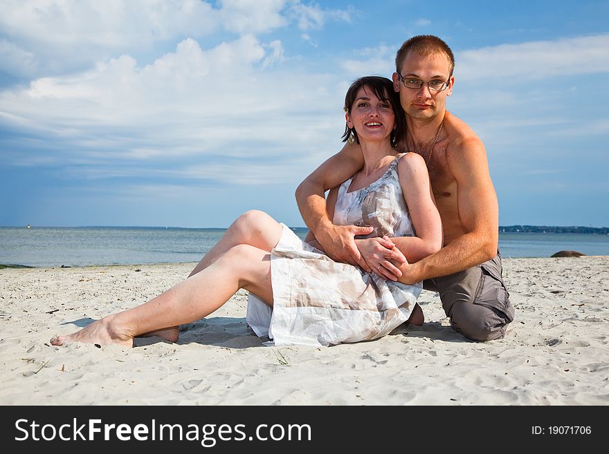 A young couple sitting together on the beach. A young couple sitting together on the beach