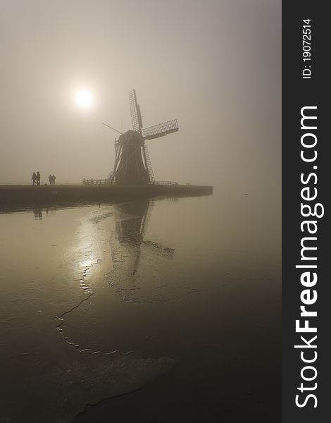 Dutch mill with hikers in the foreground in a foggy environment. Dutch mill with hikers in the foreground in a foggy environment