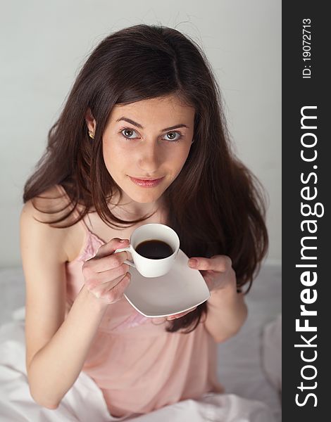 Girl with a cup of coffee looking up in the bed