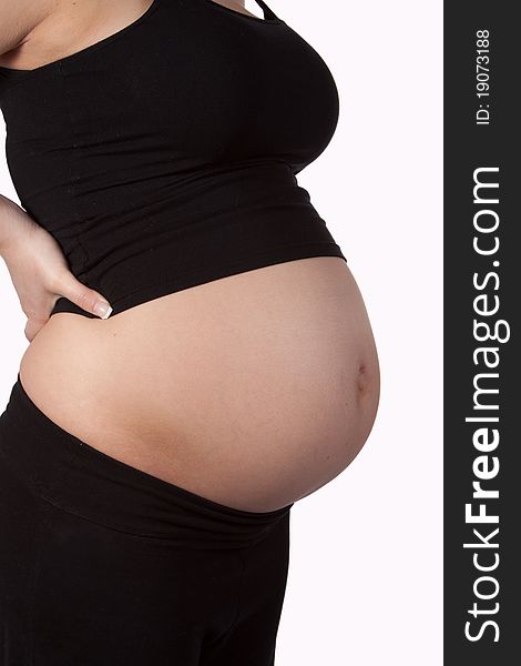 Profile of a pregnant woman's bare stomach wearing black tank and yoga pants over white. Profile of a pregnant woman's bare stomach wearing black tank and yoga pants over white