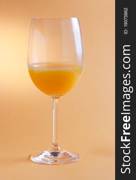 A glass of orange juice on orange background