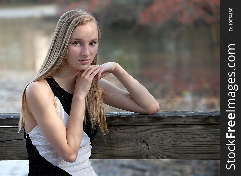 A lovely portrait of a pretty blond teenager in a natural setting and using natural light, by a lake with foliage visible in the background. A lovely portrait of a pretty blond teenager in a natural setting and using natural light, by a lake with foliage visible in the background.