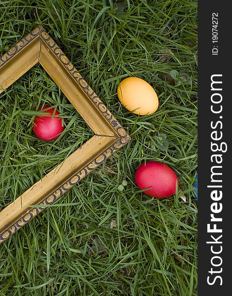 Colored eggs and wooden picture frame on grass outside. Colored eggs and wooden picture frame on grass outside.