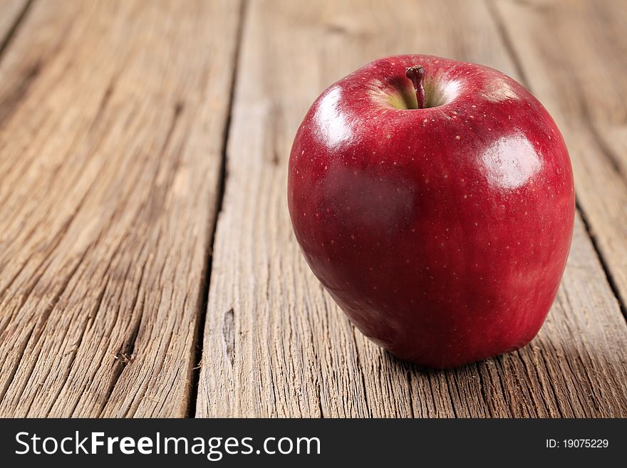 Shiny red apple on wood - closeup
