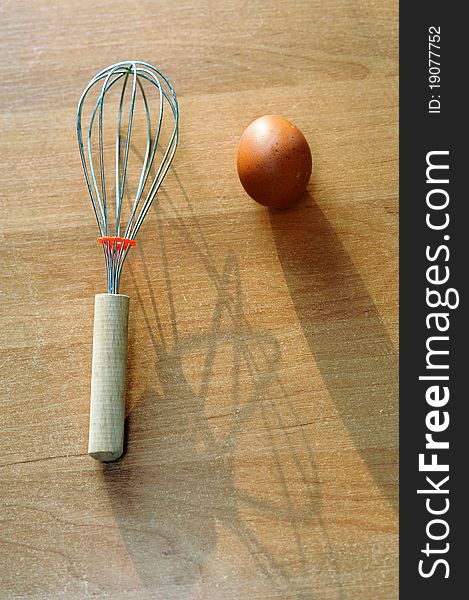 An image of an egg and a whisk on the table. An image of an egg and a whisk on the table