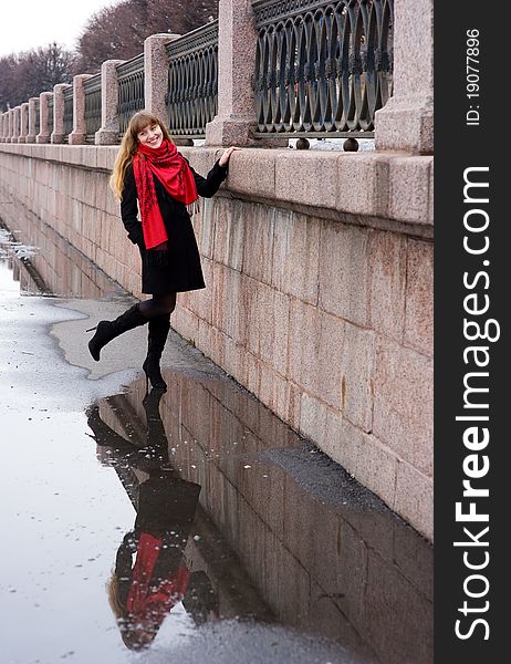 Pretty girl with long hair in red scarf and black coat and her reflection. Pretty girl with long hair in red scarf and black coat and her reflection