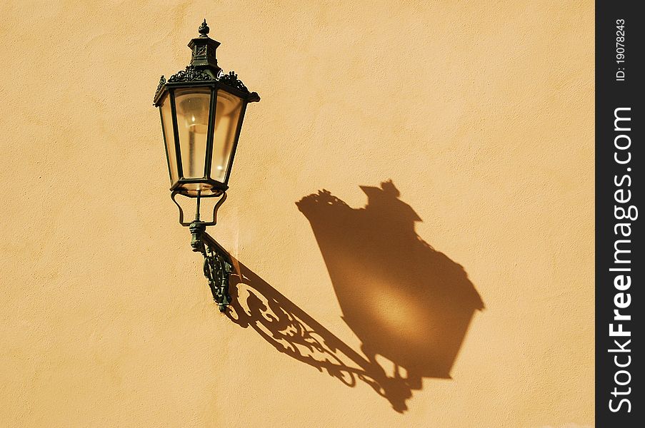 Wrought-iron lantern with its shadow on the yellow wall, Prague, Czech Republic