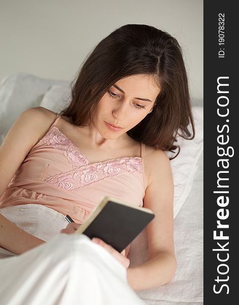 Young Woman With Notebook In Bed