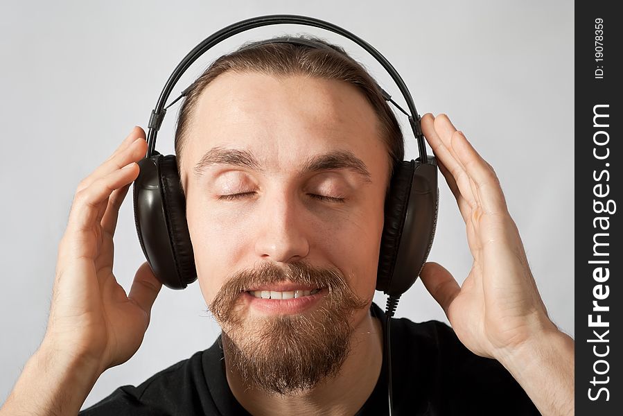 Young man in headphones with closed eyes listening to the music