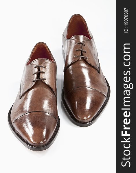 A pair of brown men leather shoes on a white floor. A pair of brown men leather shoes on a white floor