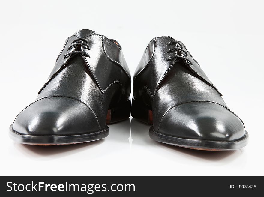 A pair of black men leather shoes on a white floor. A pair of black men leather shoes on a white floor