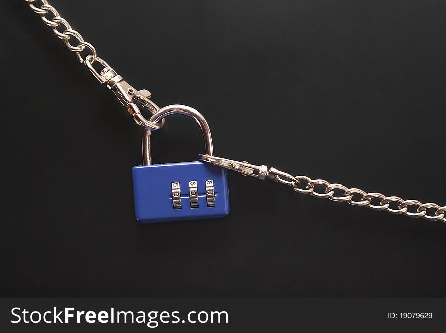 Blue combination padlock hanging on black background with metal chains. Blue combination padlock hanging on black background with metal chains