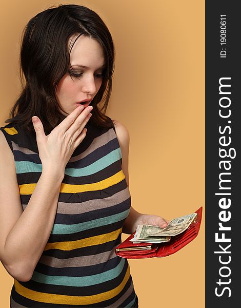 The girl holds a purse with money and surprised. The girl holds a purse with money and surprised