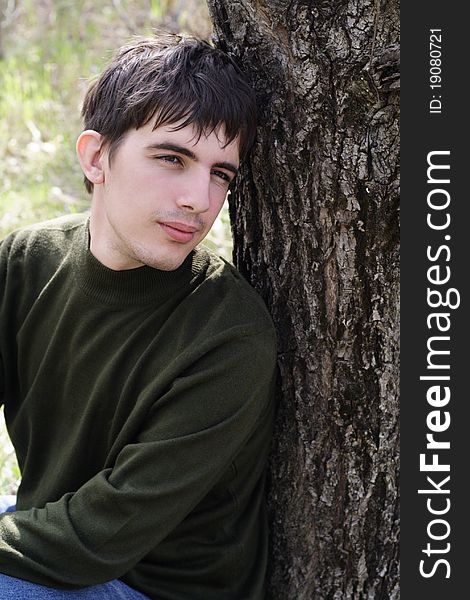 The thoughtful young man sits having leaned against a tree