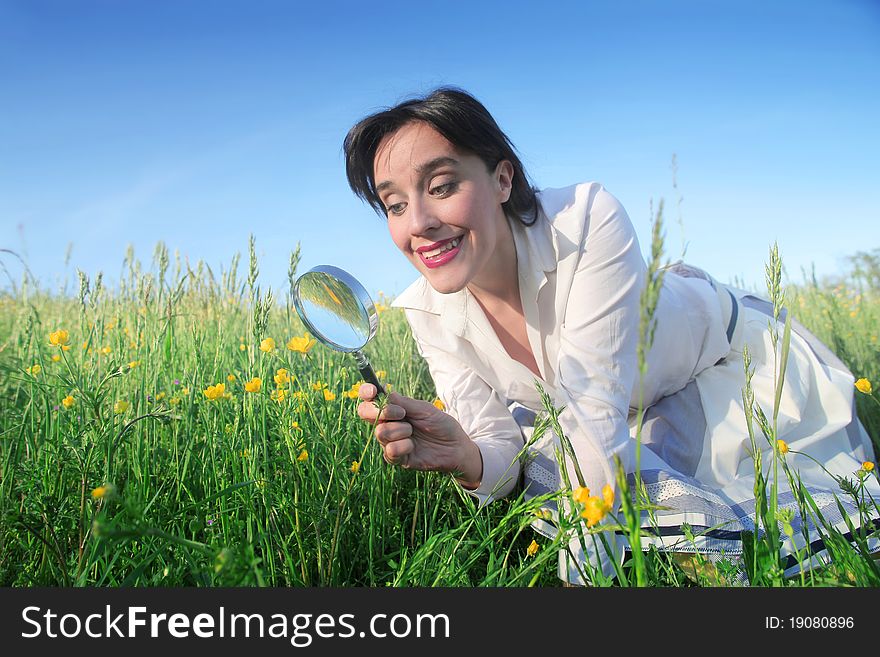 Smiling woman observing flowers through a magnifying glass. Smiling woman observing flowers through a magnifying glass