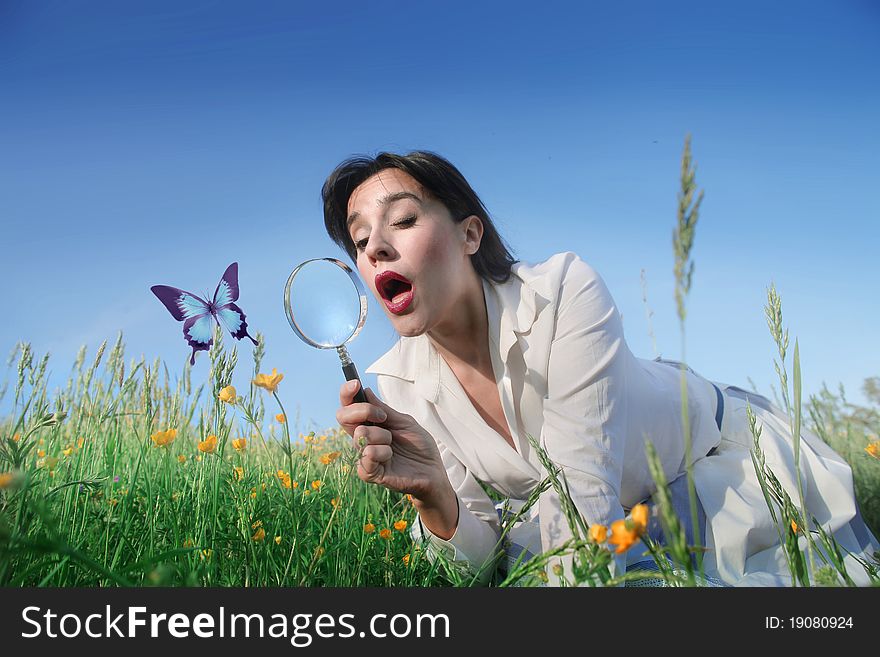 Astonished woman observing a butterfly through a magnifying glass